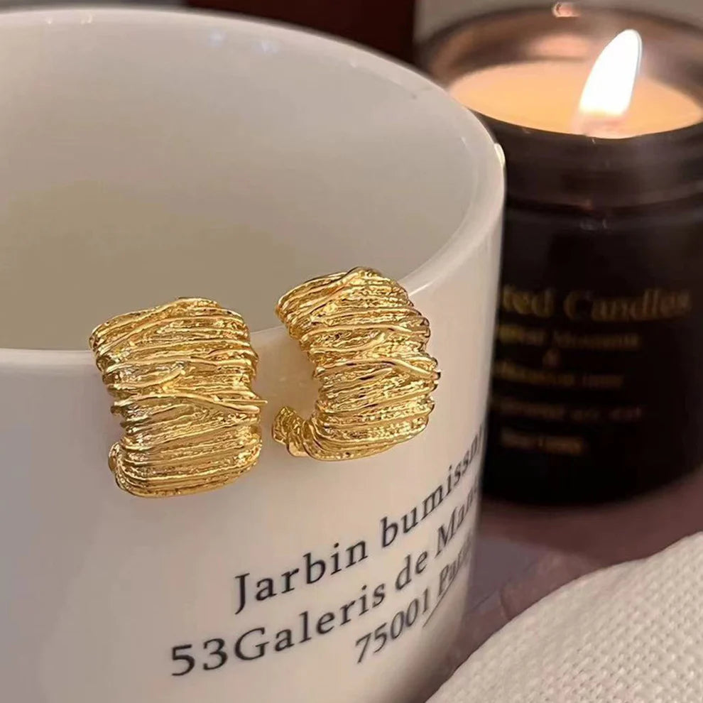 Side-profile view showing the lightweight hollow construction and post layout of the gold drop earrings.