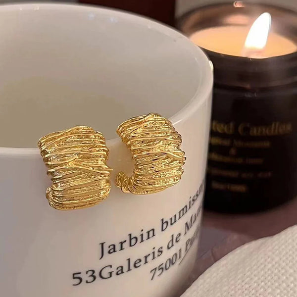 Side-profile view showing the lightweight hollow construction and post layout of the gold drop earrings.